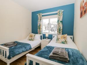 twee bedden in een kamer met blauwe muren en een raam bij Claife Heights in Windermere