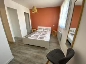 1 dormitorio con cama, espejo y silla en Maison joliment rénovée à 5 minutes du futuroscope, en Chasseneuil-du-Poitou