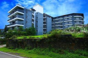 a tallartment building in front of a building at Vista Apartment Mariners Blue in Nuwara Eliya