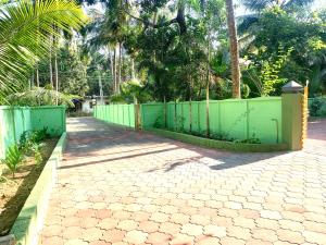 a green fence in front of a walkway at Airavatham Apartments in Guruvāyūr
