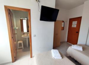 a room with two beds and a television on the wall at Hostal Neus in Alcalá de Chivert