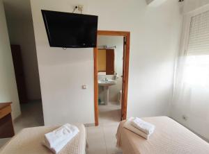 a room with two beds and a television on the wall at Hostal Neus in Alcalá de Chivert