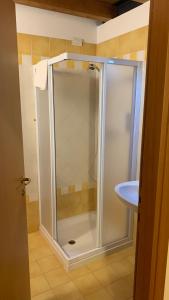 La salle de bains est pourvue d'une douche avec une porte en verre. dans l'établissement Agriturismo La Palazzina, à Castelnuovo del Garda