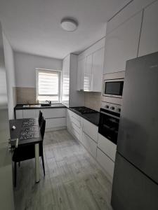 una cucina con armadi bianchi, tavolo e frigorifero di KronBed Apartments a Braşov