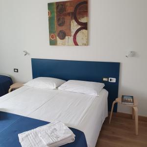 a bedroom with a white bed with a blue headboard at Hotel Pixunte in Policastro Bussentino