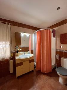a bathroom with an orange shower curtain and a sink at Vivienda Rural Villa Ruben in Jaén
