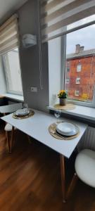 a white table with two plates on it in front of a window at Teodora B. Apartament in Liepāja