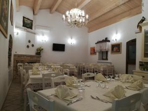 a dining room with white tables and chairs and a chandelier at Tenuta De Luca in Sannicandro Garganico