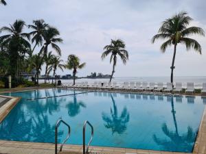 - une piscine avec des palmiers et l'océan dans l'établissement The Arena Tanjung Tuan Port Dickson, à Port Dickson