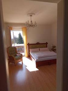 a bedroom with a bed and a chair and a chandelier at Pension Baron Schoeneck in Karlovy Vary