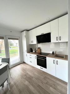 a kitchen with white cabinets and a large window at Centre Apartment in Druskininkai