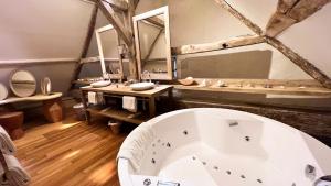 La salle de bains est pourvue d'une grande baignoire et d'un grand miroir. dans l'établissement Hôtel du Château du Rivau, à Lémeré