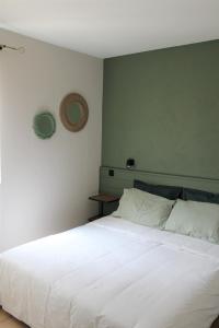 a bedroom with a white bed with a green wall at Bastidon avec piscine Gordes Lubéron in Gordes