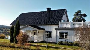 a white house with a black roof at Sjöbo, Urlaub direkt am See in Rattsjöberget