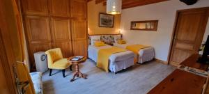 a bedroom with two beds and a table and a chair at Le Relais de la Comté in Portbail