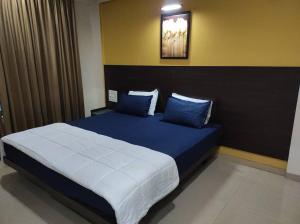 1BHK AC Service Apartment 115 في بيون: غرفة نوم بسرير كبير مع وسائد زرقاء