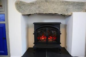 a black fireplace with a rock above it at Dol Bach - Your homely Welsh Cottage in the Heart of Snowdonia in Blaenau-Ffestiniog