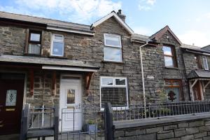 a stone house with a white door at Dol Bach - Your homely Welsh Cottage in the Heart of Snowdonia in Blaenau-Ffestiniog