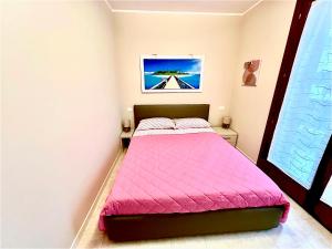 a bedroom with a bed with a pink comforter at PETITE MAISON in Sirmione