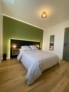 - une chambre avec un grand lit et un mur vert dans l'établissement Home Sevrier, à Sévrier