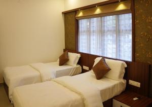 um quarto de hotel com duas camas e uma janela em Feliz Homes Kottakkal em Kottakkal