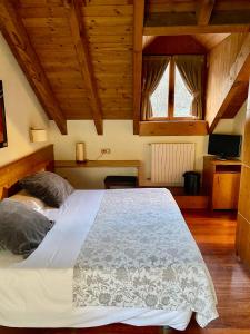 Cama grande en habitación con techo de madera en Hotel Riberies & SPA en Llavorsí