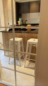 a kitchen with two white stools and a counter at Moderno alojamiento completo en pleno centro de Zaragoza in Zaragoza