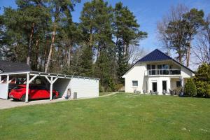 ein Haus mit einer Garage und einem roten Auto darin in der Unterkunft Ferienwohnung Thuja in Wandlitz