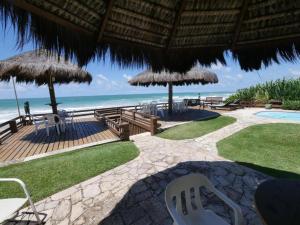 a patio with chairs and umbrellas on the beach at Mar a Vista in Porto De Galinhas