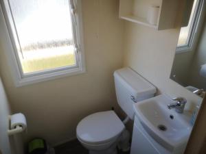 a small bathroom with a toilet and a sink at Caravan L25 in Mablethorpe +3 photos