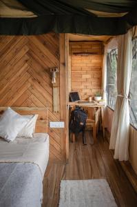 a bedroom with a desk and a bed in a wooden cabin at DugDug Camps - Glamping Amidst Nature in Bhīm Tāl