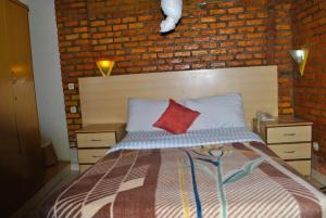 - une chambre avec un lit et un mur en briques dans l'établissement Hôtel Saint Jean Leopold, à Kigali