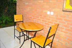 einen Holztisch und Stühle neben einer Ziegelwand in der Unterkunft Hôtel Saint Jean Leopold in Kigali