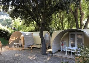a tent with a table and chairs under a tree at camping feniglia in Monte Argentario
