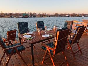 a wooden table and chairs on a dock next to the water at House ThoNi in Gornji Štoj