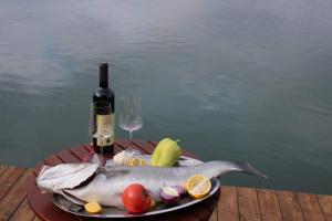 a plate with a fish and a bottle of wine at House ThoNi in Gornji Štoj