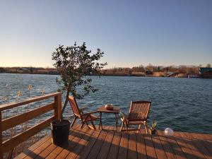 two chairs and a table on a dock next to a lake at House ThoNi in Gornji Štoj
