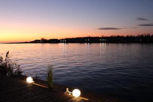 a sunset over a lake with lights on a dock at House ThoNi in Gornji Štoj