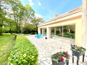 un patio con sillas azules y flores en Les Jardins de la Muse, piscine couverte, spa et fitness en Basse-Goulaine