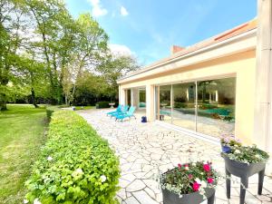 eine Terrasse mit blauen Stühlen und Blumen in einem Hof in der Unterkunft Les Jardins de la Muse, piscine couverte, spa et fitness in Basse-Goulaine