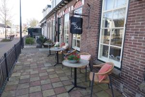 un patio avec des tables et des chaises à l'extérieur d'un bâtiment dans l'établissement Hotel het Anker van Texel, à De Cocksdorp