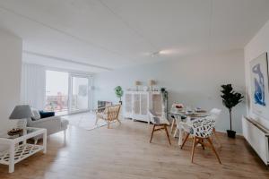 een witte woonkamer met een tafel en stoelen bij Stijlvol appartement op strand Makkum in Makkum