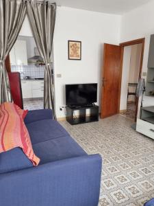 sala de estar con sofá azul y TV en Casa sul mare Porto Torres III en Porto Torres