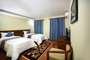 una camera d'albergo con due letti e una televisione di Karma Hotel Nepal a Kathmandu