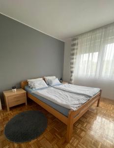 een slaapkamer met een groot bed met witte lakens en een tapijt bij Apartman Prima Sombor in Sombor