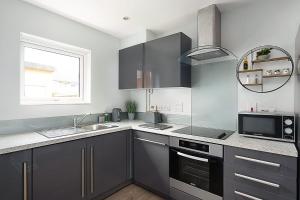 a kitchen with gray cabinets and a sink and a window at Stylish Serviced Apartment in Reading in Reading