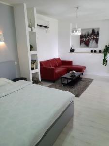 um quarto branco com uma cama e um sofá vermelho em Sharvit Hakesem em Livnim