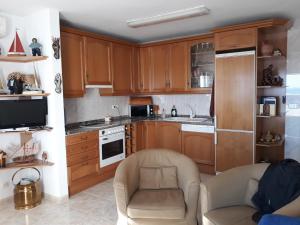 a kitchen with wooden cabinets and a couch and a chair at Nautic in L'Ametlla de Mar