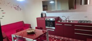 a red kitchen with a red couch and a table at Giusy's Place 2.0 in Campofelice di Roccella +9 photos