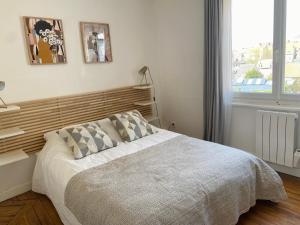 sypialnia z łóżkiem z drewnianym zagłówkiem i oknem w obiekcie 2nd floor Cozy Central Flat with free parking w mieście Boulogne-sur-Mer